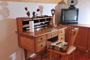 a wooden desk with a tv and a vase with flowers on it at Vineyard Cottage Keglic in Šmarje pri Jelšah
