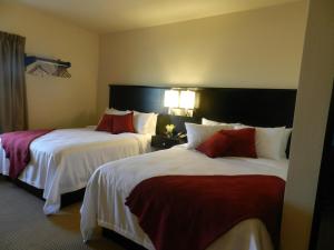 a hotel room with two beds with white and red pillows at Black Gold Suites in Tioga