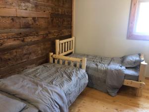 1 dormitorio con 2 camas y pared de madera en Mini-Mooh cabin en Clearwater