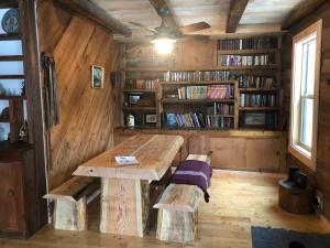a room with a wooden table and benches and bookshelves at Mini-Mooh cabin in Clearwater
