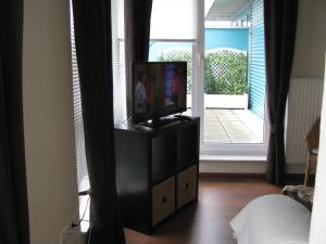 a television on a stand in a room with a window at Apartment am Steinweg in Emden
