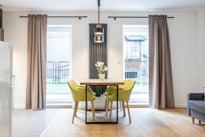 a dining room with a table and yellow chairs at ApartSatiDeluxe in Pasłęk