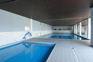 a large swimming pool with blue water in a building at relax @the beach in De Haan