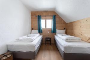 two beds in a small room with a window at Chalet les Vieux Murs in L'Alpe-d'Huez