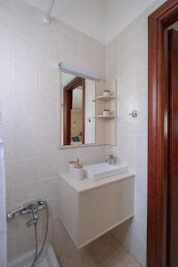 ein weißes Badezimmer mit einem Waschbecken und einem Spiegel in der Unterkunft Studio Dieci in Drama