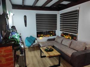 a living room with a couch and a table and two windows at Drinski oganj kuca za odmor in Bajina Bašta