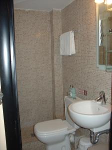 a bathroom with a white toilet and a sink at Hotel Strimoniko in Asprovalta