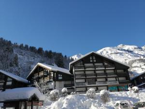 ein großes Gebäude mit Schnee und Bergen im Hintergrund in der Unterkunft Studio Les Contamines Montjoie - Les Combettes - Le Lay - WIFI INCLUS in Les Contamines-Montjoie