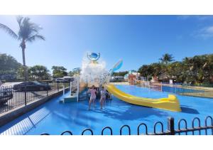 a person in a swimming pool with a surfboard at Discovery Parks - Coolwaters, Yeppoon in Kinka