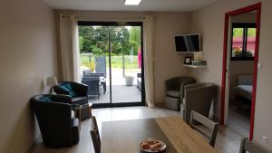 a living room with a table and chairs and a sliding glass door at Le Chalet de l'Authie in Saulchoy