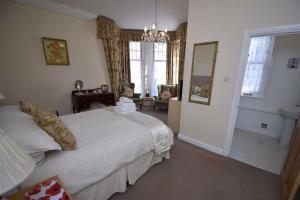 a bedroom with a bed and a chair and a mirror at Three Gables in Bridlington