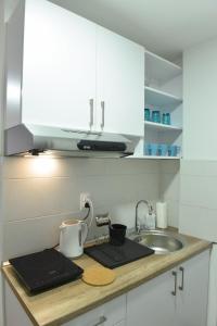 encimera de cocina con fregadero y armarios blancos en Central Apartment, en Ćuprija