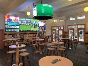 a restaurant with tables and stools and a large screen at Criterion Hotel Sydney in Sydney