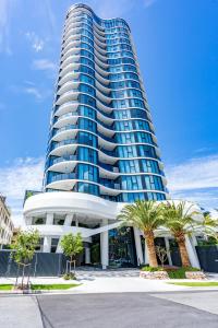 a tall blue building with palm trees in front of it at The Gallery Broadbeach - GCLR in Gold Coast