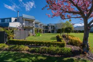 una casa con un patio con un árbol en ASURE Explorer Motel & Apartments, en Te Anau