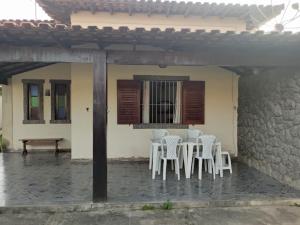 un patio con sillas blancas y una mesa y un edificio en Casa Area Gourmet, en Araruama