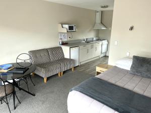 1 dormitorio con cama, mesa y cocina en Jade Court Motel, en Hokitika