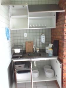 uma cozinha com um balcão com electrodomésticos brancos em Casinha no Sal - Tangaroa Residencial em Salinópolis