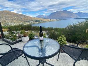 a table with two wine glasses and a bottle of wine at Luckie Lane Homestay in Queenstown