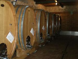 une rangée de barils de vin dans une cave dans l'établissement Agriturismo Giorgio Colutta, à Manzano