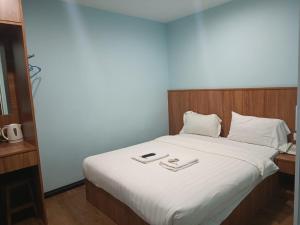 Una cama con sábanas blancas y dos bandejas. en AMBASSADOR LABUAN VIEW HOTEL, en Victoria Town