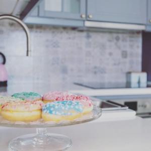 four donuts with sprinkles on a glass plate on a counter at The Little White House, Suite Flower Beach 9 in Playa Honda