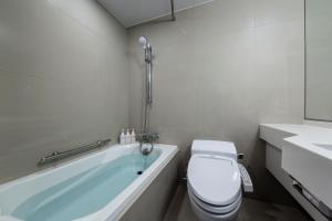 a white bathroom with a toilet and a bath tub at The Royal Park Hotel Kyoto Sanjo in Kyoto