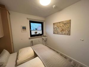 ein kleines Schlafzimmer mit einem Bett und einem Fenster in der Unterkunft Margaritenhaus Heinze in Westerland