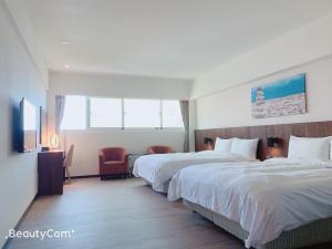a hotel room with two beds and a television at Seeing Inn in Taitung City