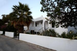 a white house with a white fence and a palm tree at Moscha Studios in Batsi