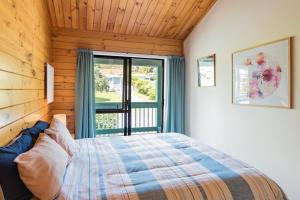 a bedroom with a bed and a large window at Bay of Islands Lodge in Paihia