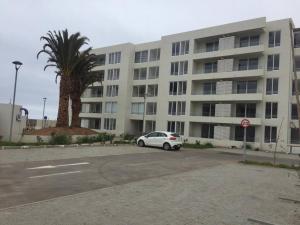 Departamento de descanso frente al mar في لا سيرينا: سيارة بيضاء متوقفة أمام مبنى كبير