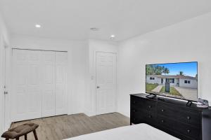 Un dormitorio con paredes blancas y un tocador con TV. en CryptoCabana en Miami