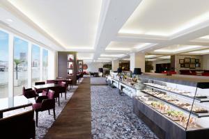 a restaurant with a buffet line with tables and chairs at Kobe Meriken Park Oriental Hotel in Kobe