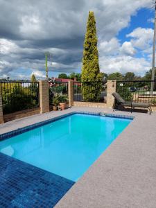 una piscina de agua azul frente a una valla en Settlers Motor Inn, en Tenterfield