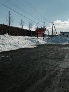 a sign on the side of a road with snow at ビジネスホテル幸楽 in Abashiri