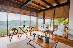 een woonkamer met een tafel, stoelen en ramen bij Glenross Living in Kalutara