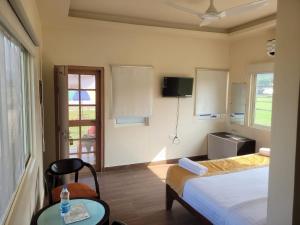 a bedroom with a bed and a table and a window at Corbett VEDA INN in Rāmnagar