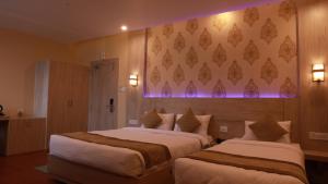 two beds in a hotel room with purple lights at Komal Hotel in Lālbhitti