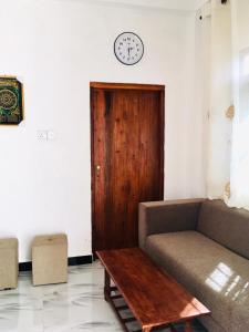 a living room with a couch and a clock on the wall at Sujeewa Holiday Resort Anuradhapura in Anuradhapura