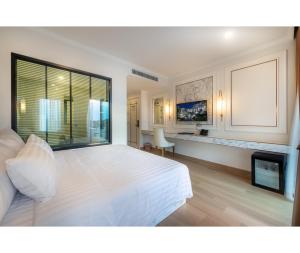 a bedroom with a large white bed and a fireplace at Nine River Hotel in Ratchaburi