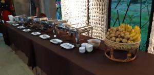 einen Tisch mit einem Haufen Essen und einem Obstkorb in der Unterkunft Radina Residence in Nakhon Si Thammarat