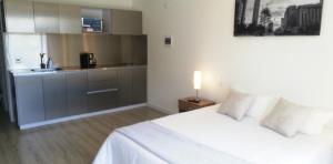 een slaapkamer met een wit bed en een keuken bij Acogedor Apartamento en Centro Internacional Bogotá in Bogota