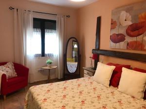 1 dormitorio con 1 cama y 1 silla roja en La Senda Del Duratón en Sebúlcor
