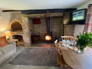 a living room with a table and a fireplace at Honeysuckle Cottage in Dorchester