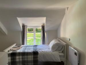 Habitación pequeña con cama y ventana en Honeysuckle Cottage, en Dorchester