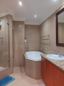 a bathroom with a tub and a sink and a shower at Ocean Sunrise at the Sails - Durban point waterfront in Durban