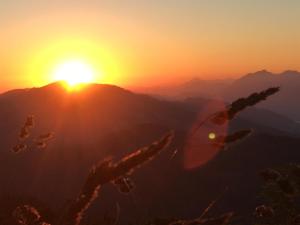 a sunset in the mountains with the sun in the sky at Apartment Mona´s Home in Sankt Pankraz