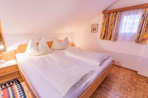 een slaapkamer met een bed met witte lakens en een raam bij City Life 6 by Alpenidyll Apartments in Schladming