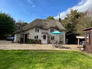 ein Haus mit einem Tisch und einem Sonnenschirm im Hof in der Unterkunft Honeysuckle Cottage in Dorchester